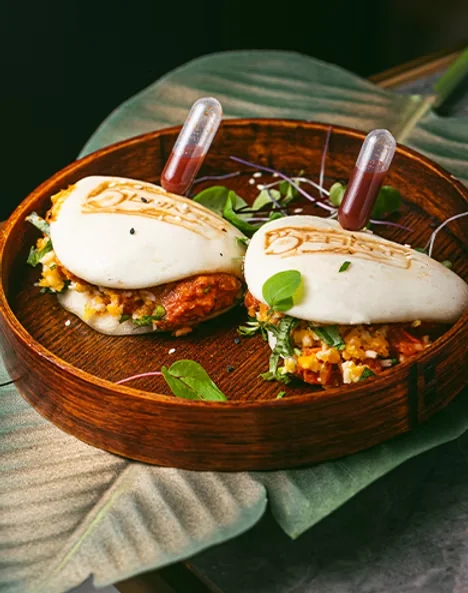 Two filled bao buns served in a wooden bowl