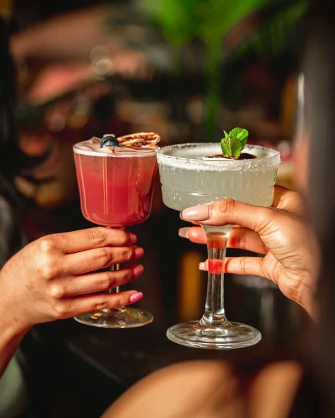 Guests raising two cocktails in a toast