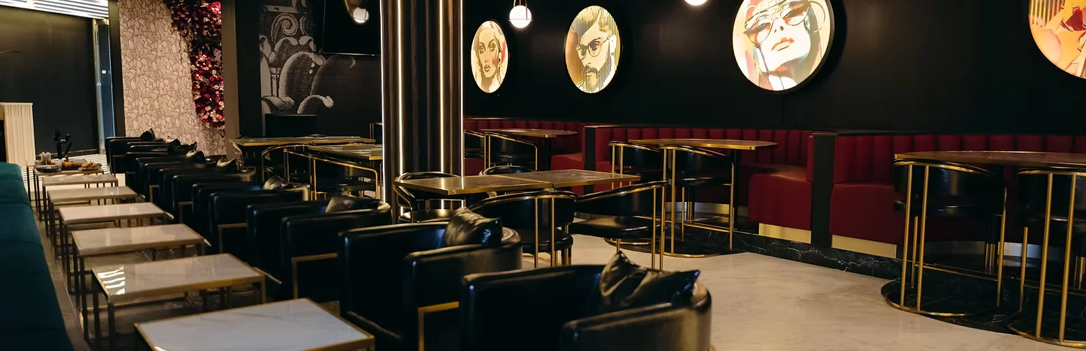 Befikre's dining room with gold-framed tables, dark armchairs, and portrait artwork